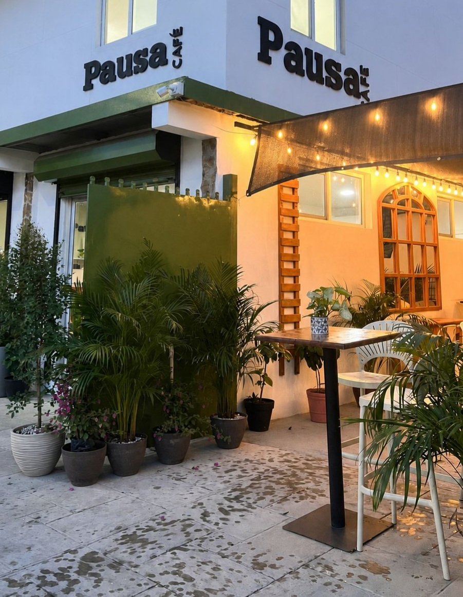 Fachada de Pausa Café en Siguatepeque con terraza, plantas e iluminación cálida